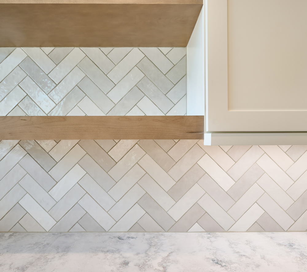 White herringbone tile backsplash extending to the ceiling in a modern kitchen with white cabinets.